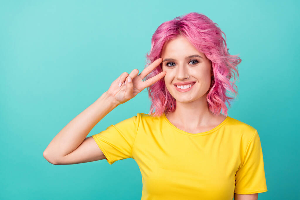 Foto von Millennial süße rosa Frisur Dame zeigen V-Zeichen tragen gelbes T-Shirt isoliert auf Krickente Hintergrund - Foto, Bild