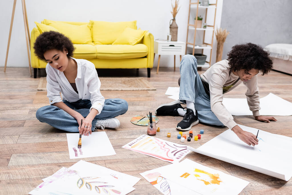 African american couple painting on papers on floor in living room  - Photo, Image