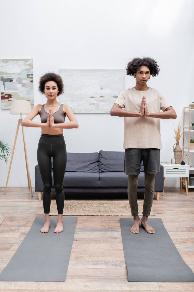 Giovane coppia afro-americana in piedi in posa yoga su stuoie a casa  - Foto, immagini