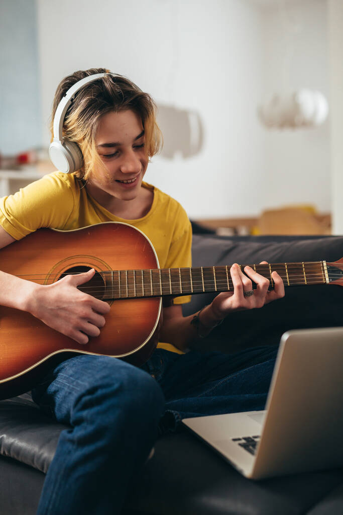 мальчик-подросток играет на акустической гитаре дома. у него онлайн-урок - Фото, изображение