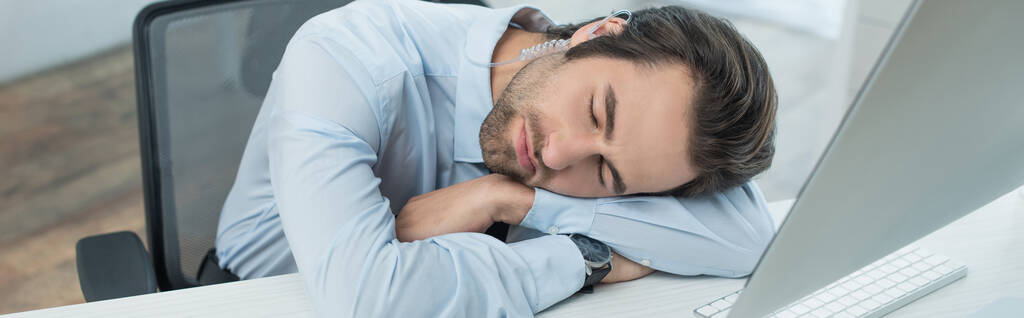 uupunut vartija nukkuu työpaikalla lähellä tietokoneen näyttö, banneri - Valokuva, kuva