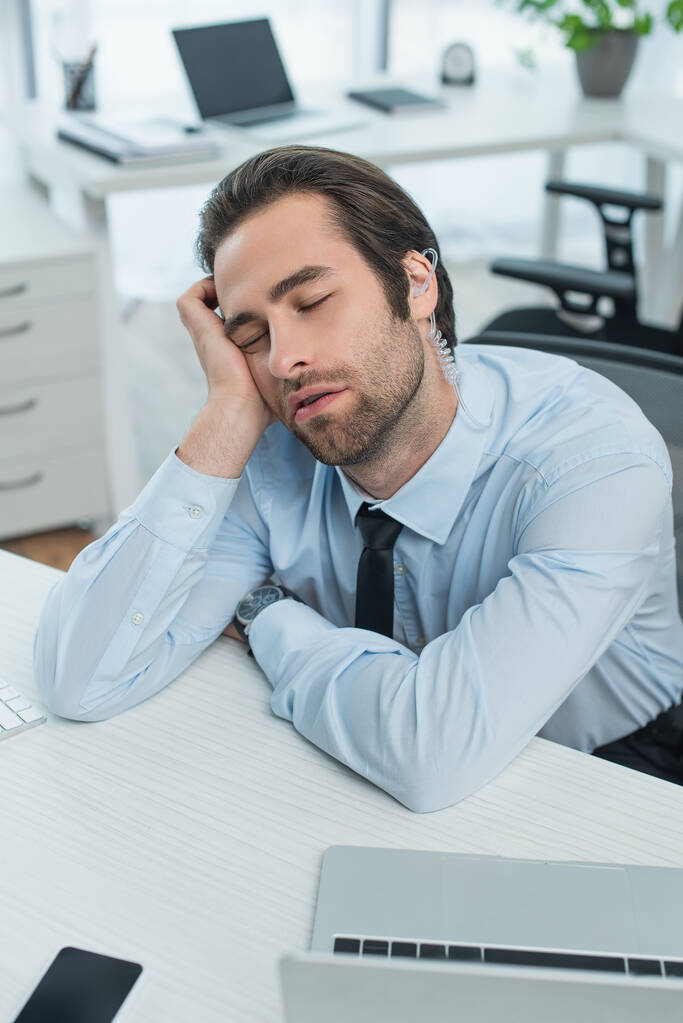 βαριέται άνθρωπος της ασφάλειας στο ακουστικό κοιμάται στο χώρο εργασίας στο γραφείο - Φωτογραφία, εικόνα