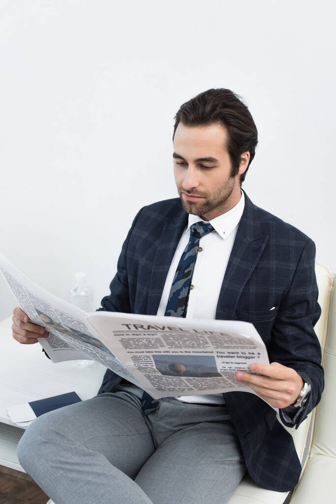 fiatal férfi olvas újságot, miközben várakozik az indulási társalgóban - Fotó, kép