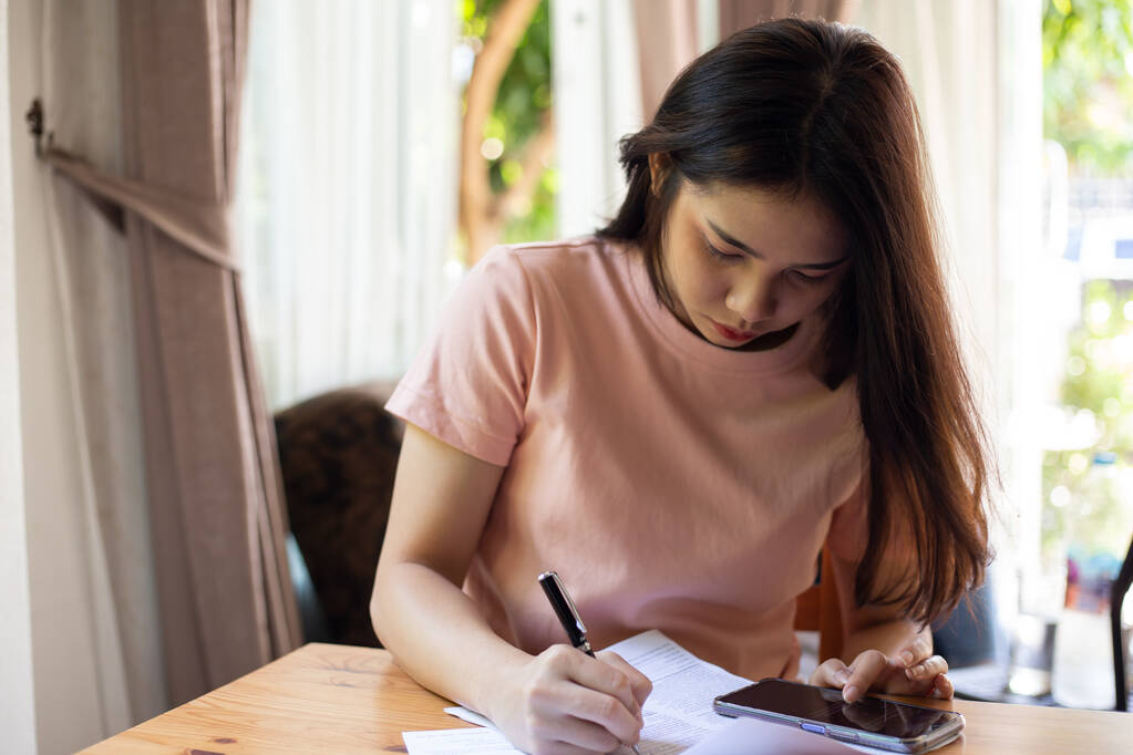 Азиатская женщина подчеркнула о работе с бумагами на столе дома - Фото, изображение