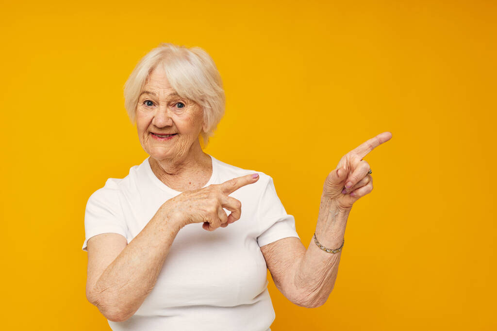 Lächelnde ältere Frau in lässiger T-Shirt-Geste mit abgeschnittenen Händen - Foto, Bild