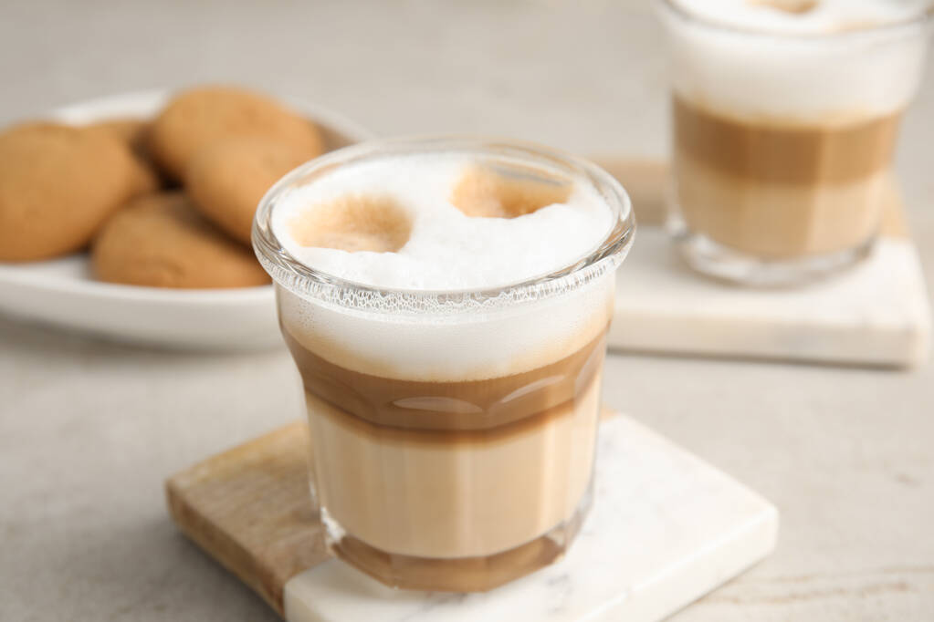 Gafas con delicioso macchiato de latte sobre mesa blanca - Foto, imagen