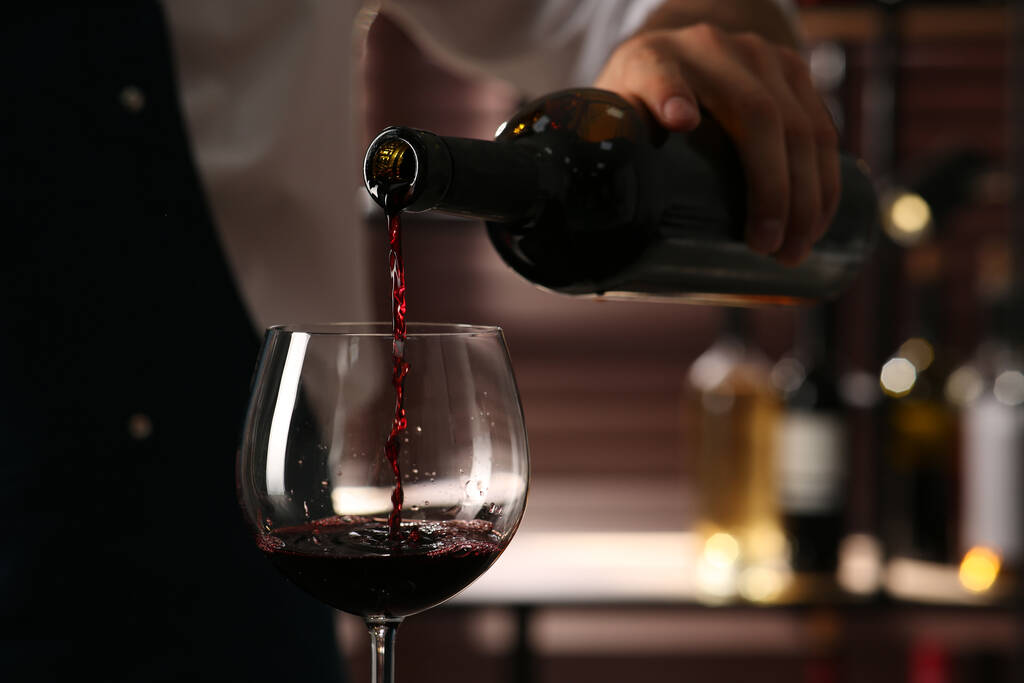 Barmen bardaklara kırmızı şarap dolduruyor, yakın plan. - Fotoğraf, Görsel