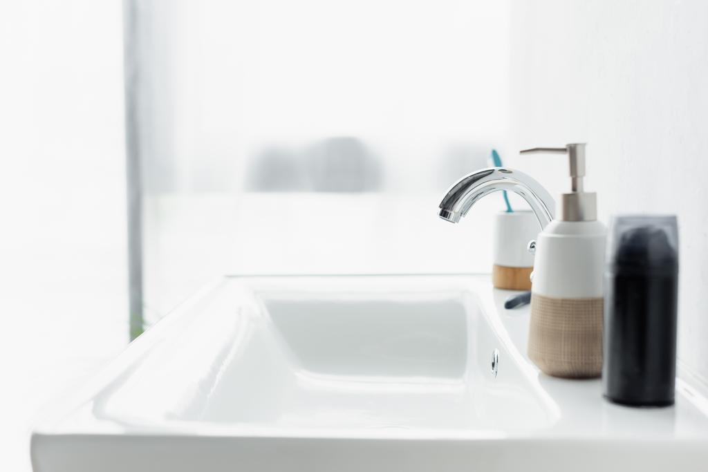 espuma de afeitar y dispensador con jabón líquido en el lavabo blanco en el baño - Foto, imagen