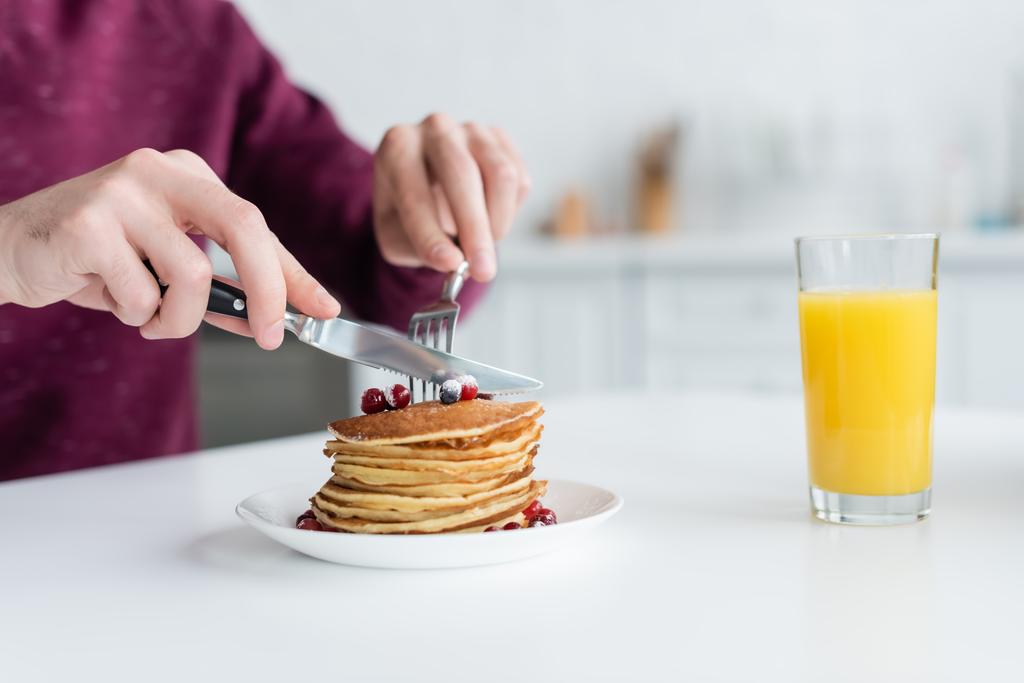 partial view of man cutting pancakes near glass of orange juice  - Photo, Image