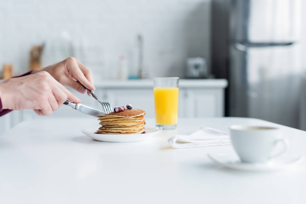 vista parziale di pancake taglio mamma vicino succo d'arancia e tazza di caffè offuscata - Foto, immagini
