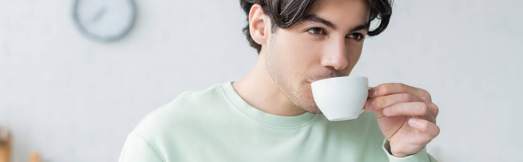 jong brunette man drinken koffie uit witte beker, banner - Foto, afbeelding