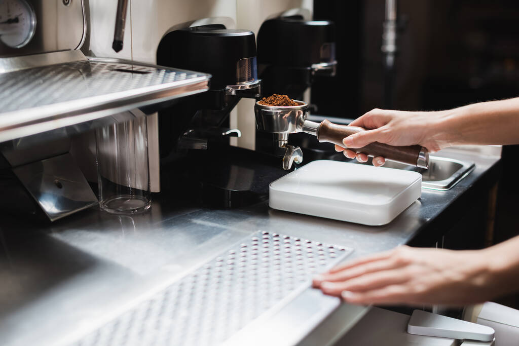 Vista recortada de barista portafilter celebración cerca de la amoladora y la máquina de café en la cafetería  - Foto, Imagen