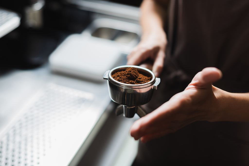 Vista recortada de barista borrosa celebración portafilter con café en la cafetería  - Foto, imagen