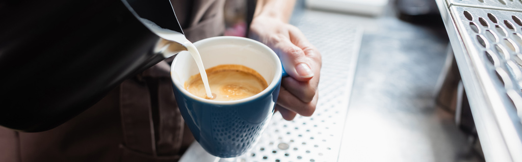Καλλιεργημένη θέα του barista ρίχνει γάλα σε καφέ στο καφέ, πανό  - Φωτογραφία, εικόνα