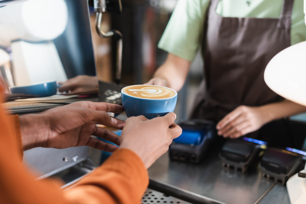 Oříznutý pohled na africký Američan drží kávu v blízkosti rozmazané barista v kavárně  - Fotografie, Obrázek