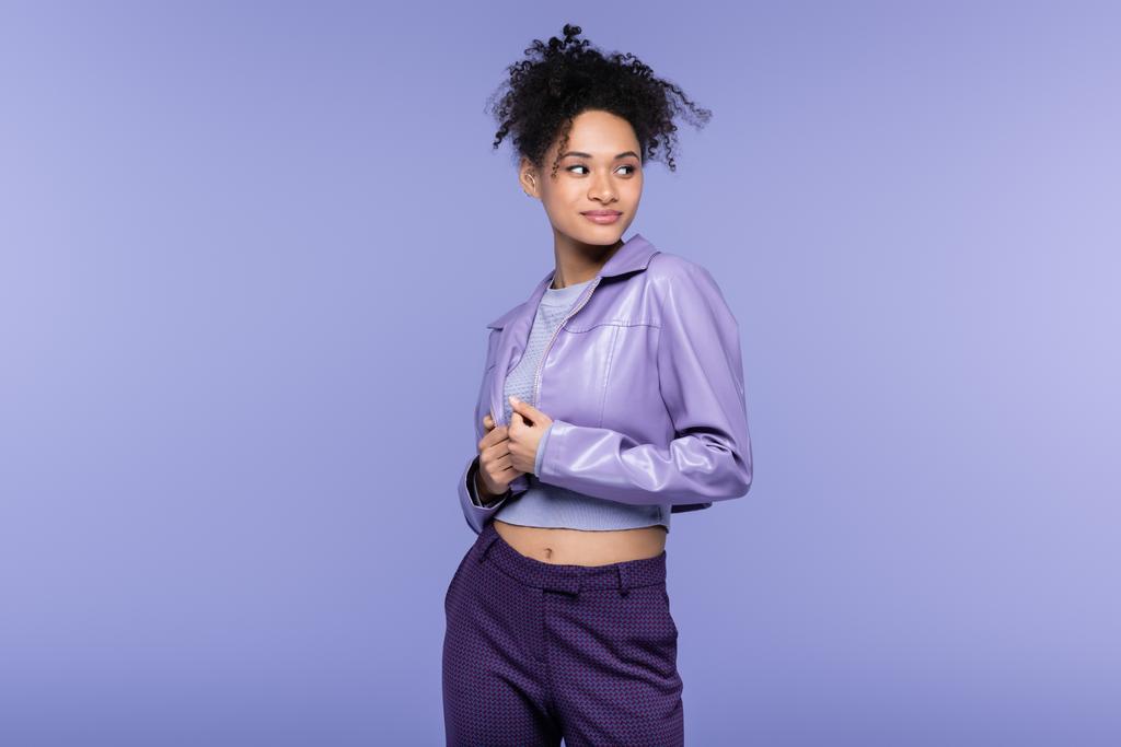 молода афроамериканка в шкіряній куртці, яка виглядає ізольованою на фіолетовому. - Фото, зображення