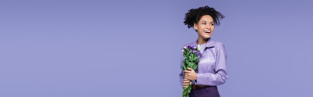 gelukkig jong Afrikaans amerikaans vrouw houden boeket van bloemen geïsoleerd op paars, banner - Foto, afbeelding