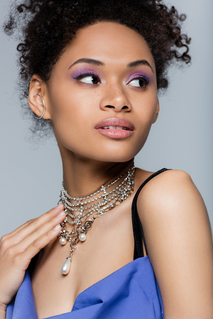 mujer afroamericana sensual con sombra de ojos púrpura aislada en gris - Foto, imagen