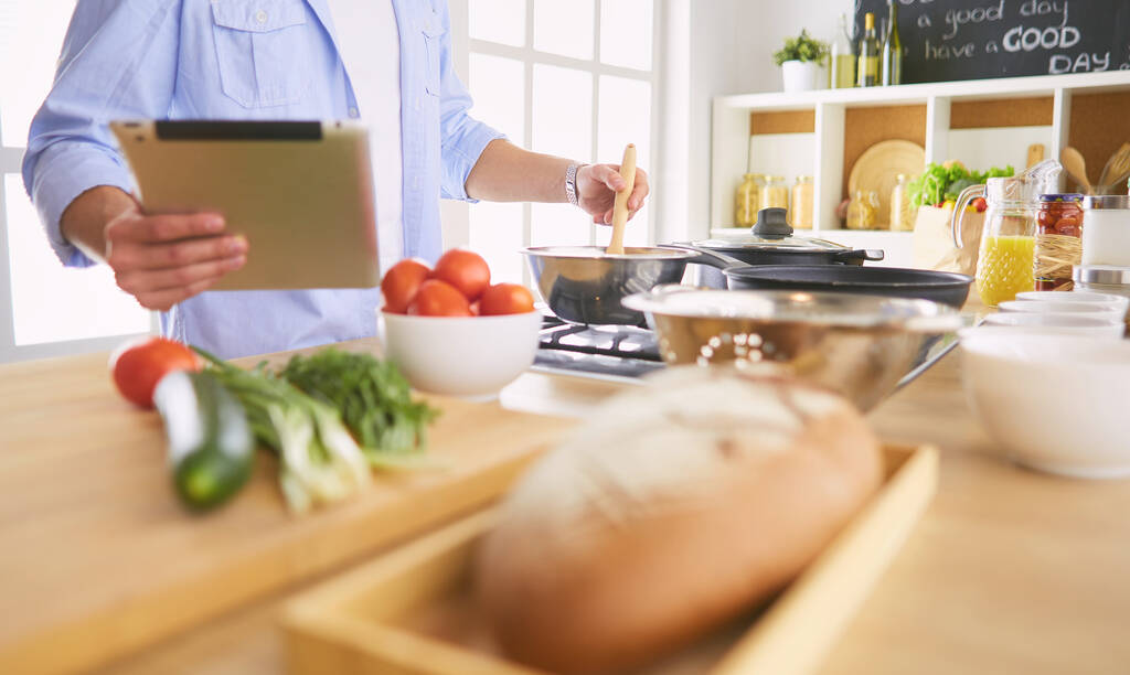 Muž po recept na digitální tablet a vaření chutné a zdravé jídlo v kuchyni doma - Fotografie, Obrázek
