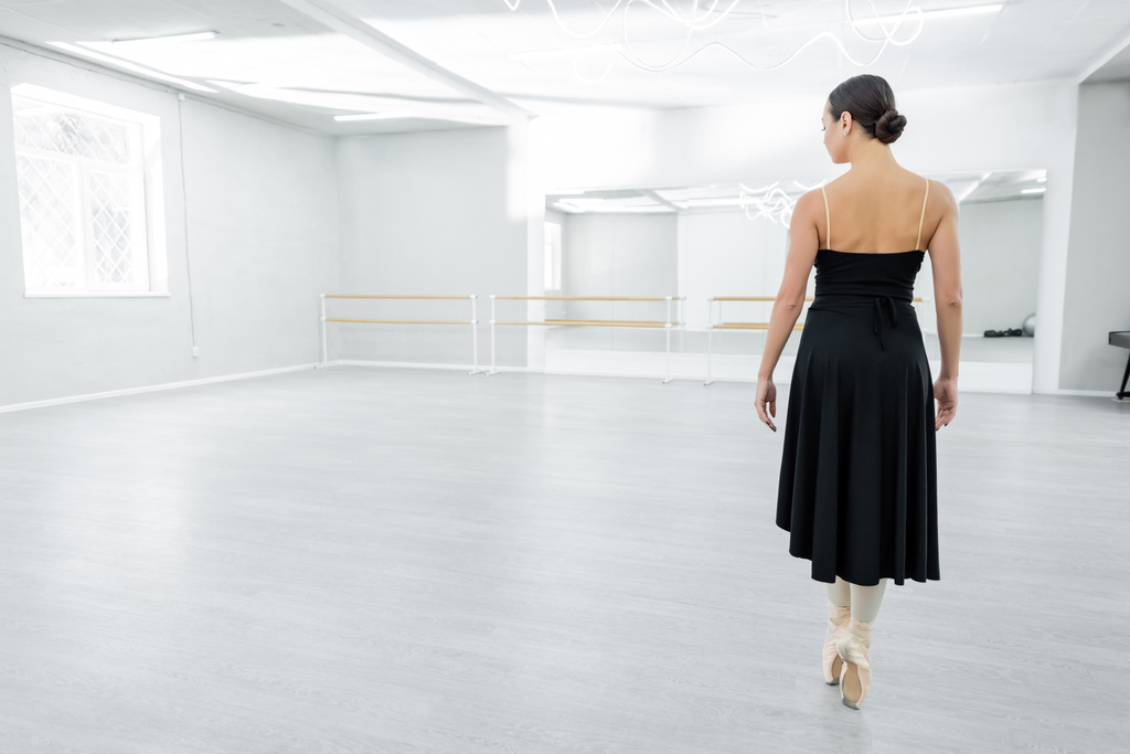 vista posteriore della ballerina in scarpe da punta in piedi sulle dita dei piedi durante la ripetizione nella sala da ballo - Foto, immagini