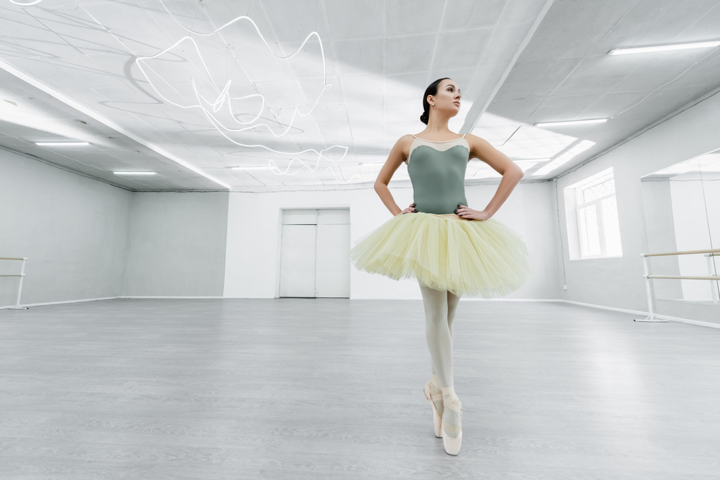 チュチュの女性の完全な長さのビューは、バレエスタジオで腰に手で踊る - 写真・画像