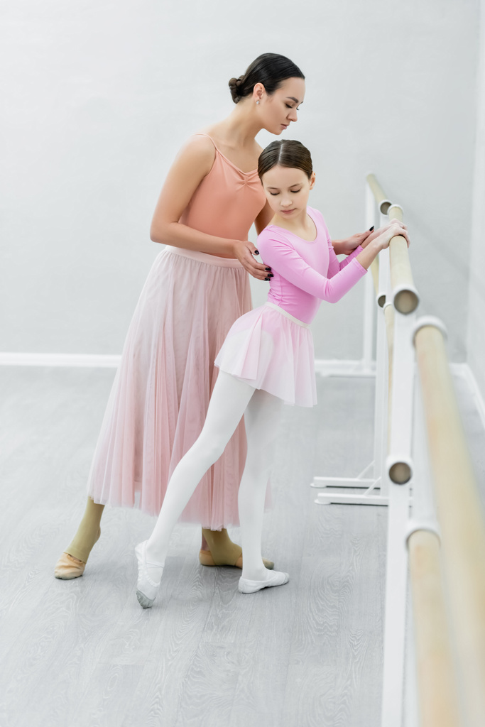 vue complète de la jeune ballerine assistant la formation de la jeune fille préadolescente en studio - Photo, image