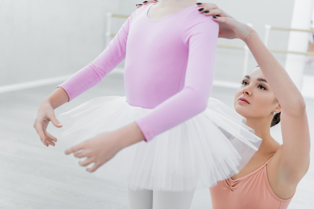 θολή κοπέλα εξάσκηση χορογραφικά στοιχεία κοντά στο νεαρό δάσκαλο μπαλέτου - Φωτογραφία, εικόνα