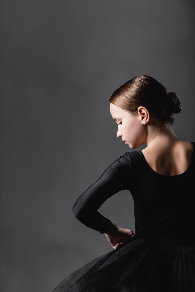 vue arrière de la fille en costume de ballet noir sur fond gris - Photo, image