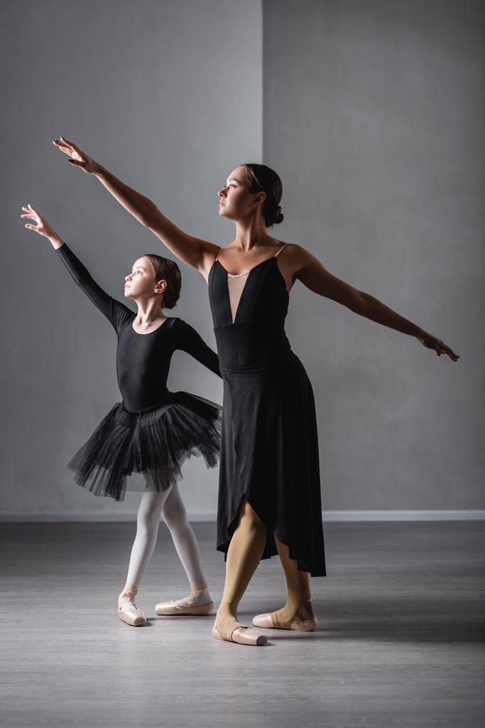 バレエ教師と黒人チュチュの少女がレッスン中に踊るのを見ると - 写真・画像