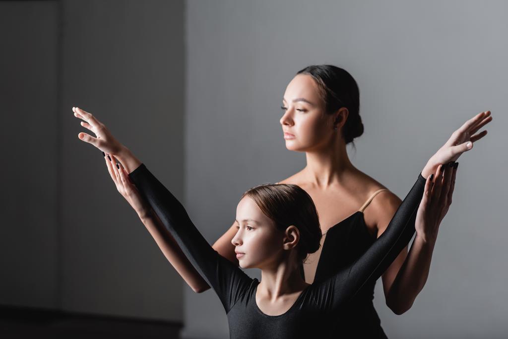 молодой учитель балета поднимает руки девушки во время урока танца - Фото, изображение