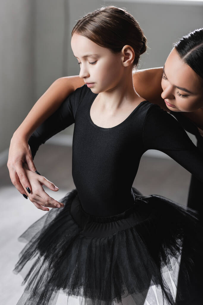 Ballettlehrerin hält Hand eines Mädchens in schwarzem Tutu während des Tanzkurses - Foto, Bild