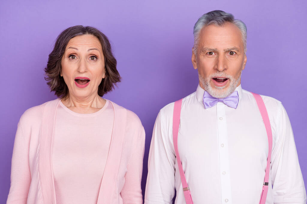 Портрет впечатленных двух пожилых людей, смотрящих безмолвно открытый рот изолирован на фиолетовом фоне цвета - Фото, изображение
