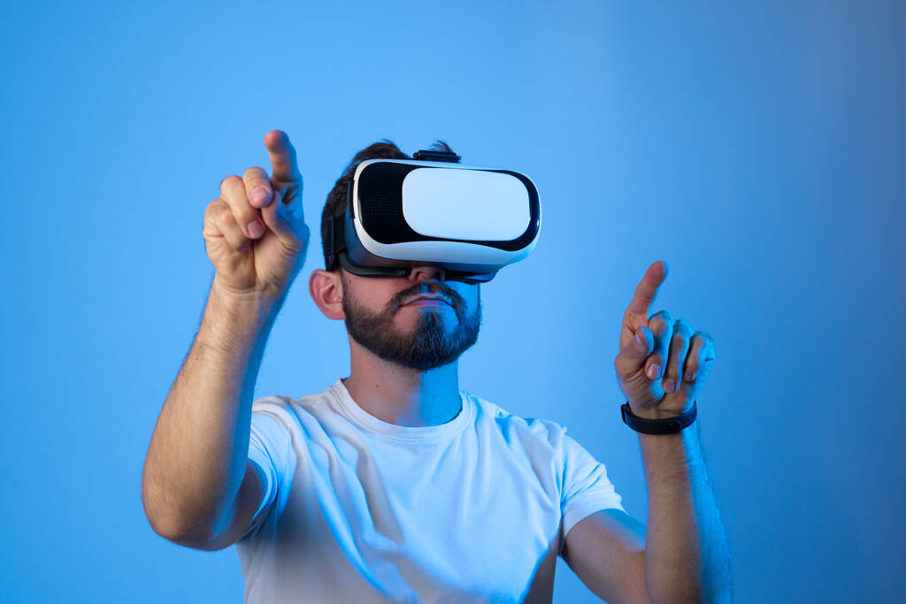 Portret van een jonge blanke man met VR-bril en interactie met virtual reality. Toekomstig technologieconcept. - Foto, afbeelding