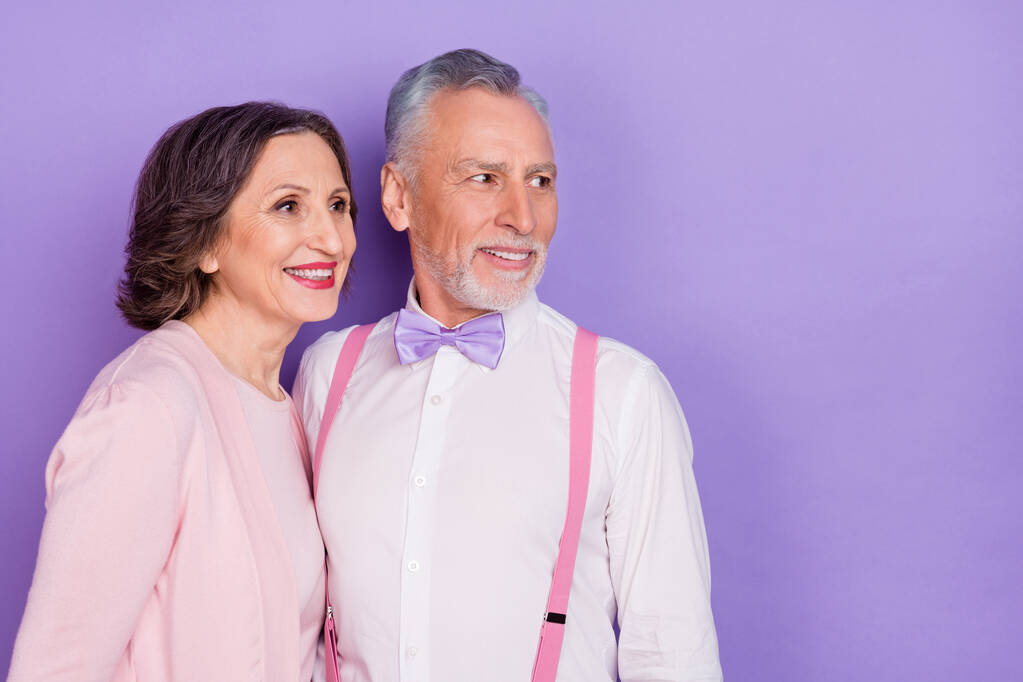 Фото двох позитивних веселих людей виглядають зацікавленими порожнім простором ізольованим на фіолетовому кольоровому фоні
 - Фото, зображення