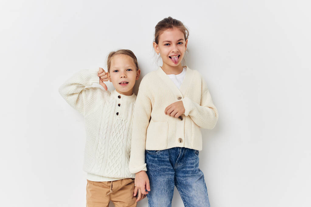 two little girls in sweaters posing childhood light background - Foto, afbeelding