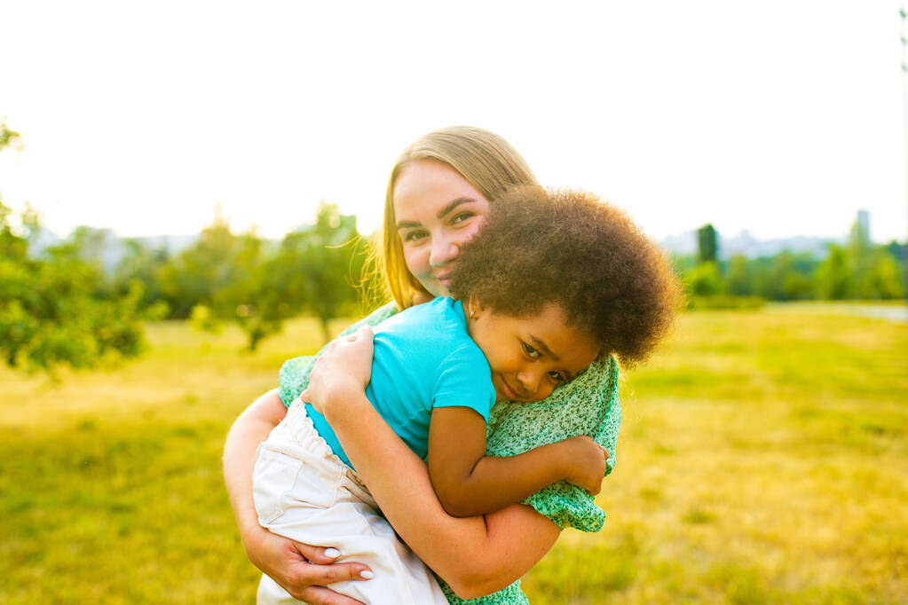 schöne süße Afro-Mädchen umarmt ihre Mutter im Frühling Park - Foto, Bild