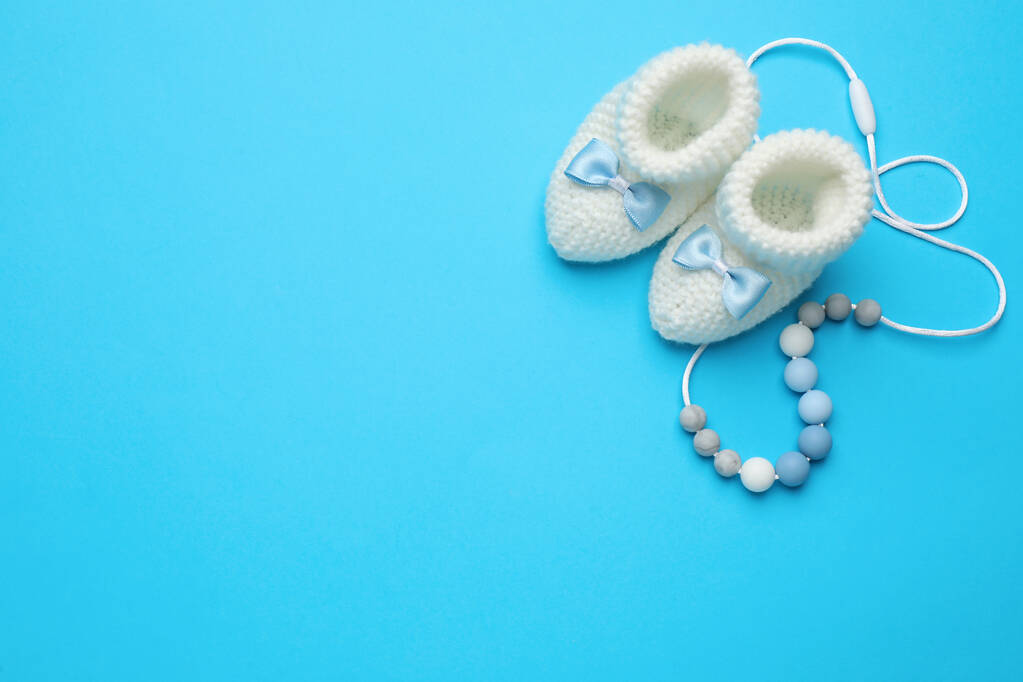 Lindos botines de bebé y juguete sobre fondo azul claro, cama plana. Espacio para texto - Foto, Imagen