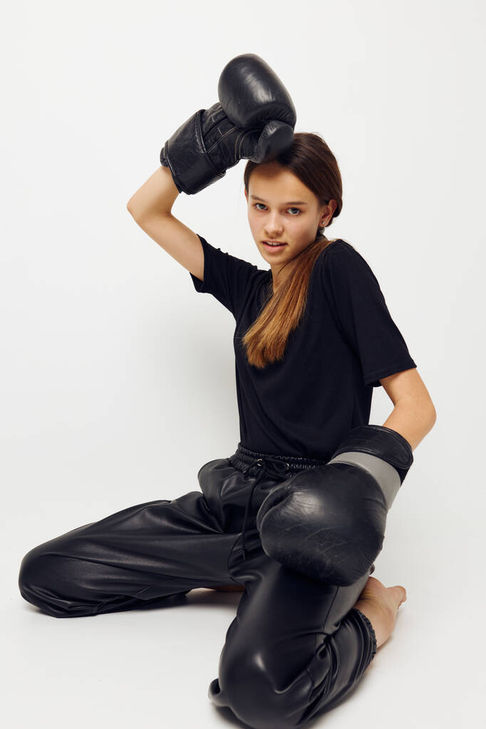 jeune femme en gants de boxe sur le sol en t-shirt noir fond isolé - Photo, image