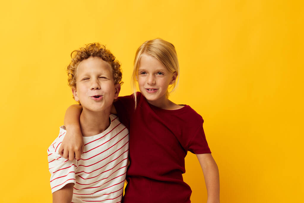 изображение положительного мальчика и девочки, стоящих бок о бок, создавая детские эмоции желтого фона - Фото, изображение