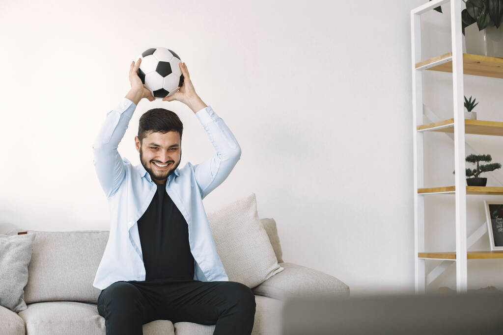 Barna srác ül az edző és nézi a focit otthon - Fotó, kép