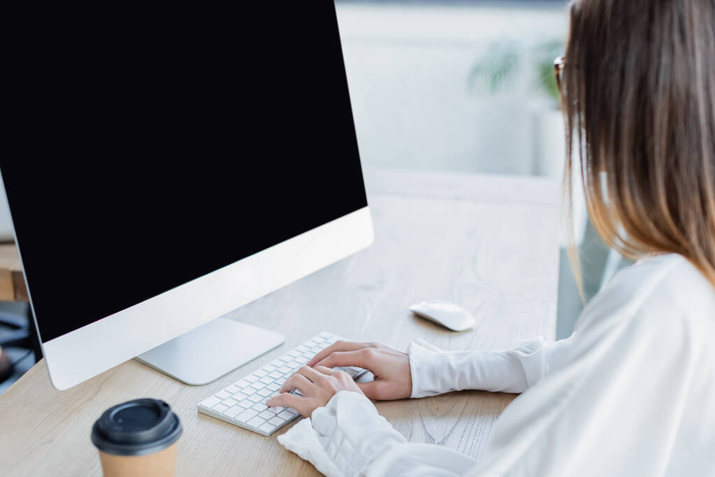 junge Geschäftsfrau tippt auf Tastatur in der Nähe des Computermonitors  - Foto, Bild