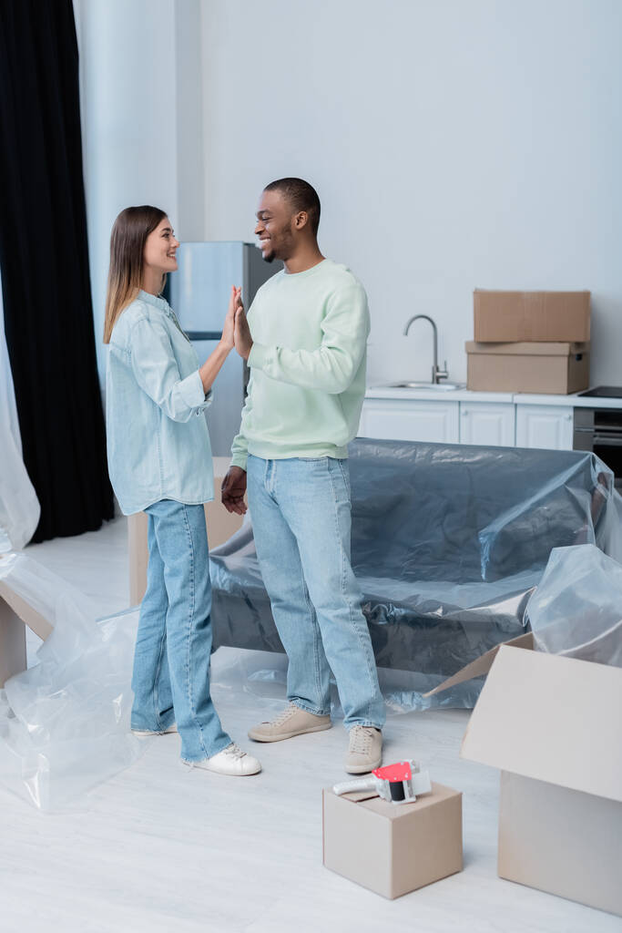 cheerful interracial couple giving high five in new apartment  - Photo, Image