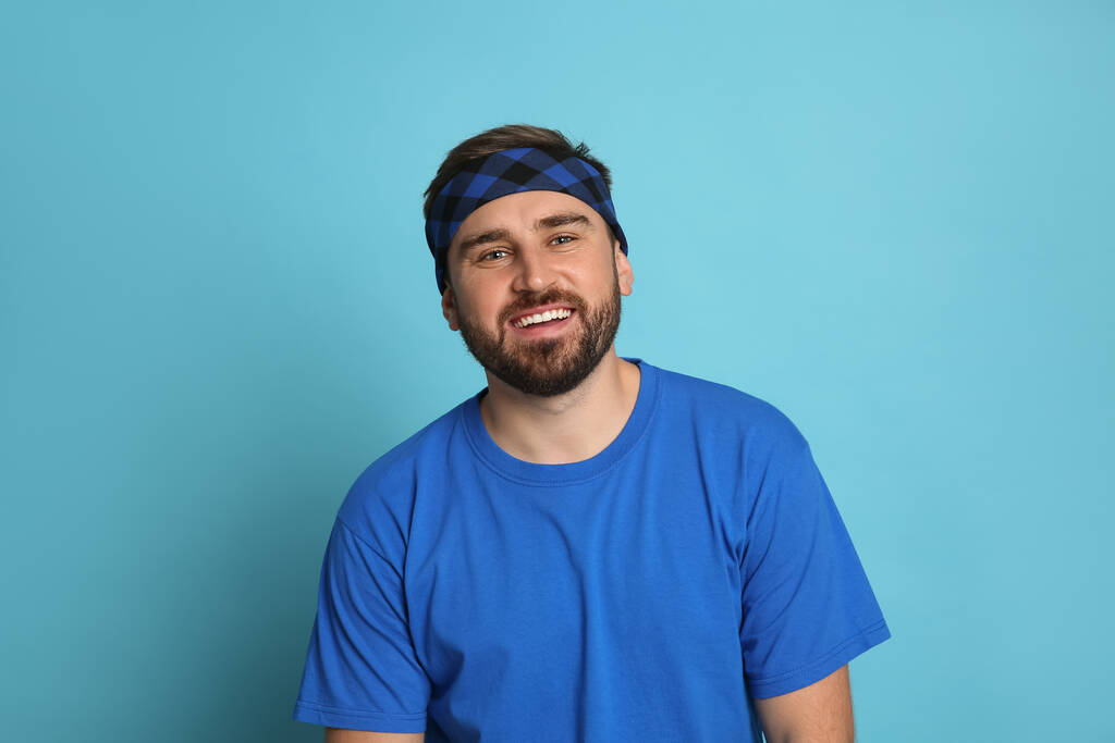 Модный молодой человек в стильной бандане на светло-голубом фоне - Фото, изображение