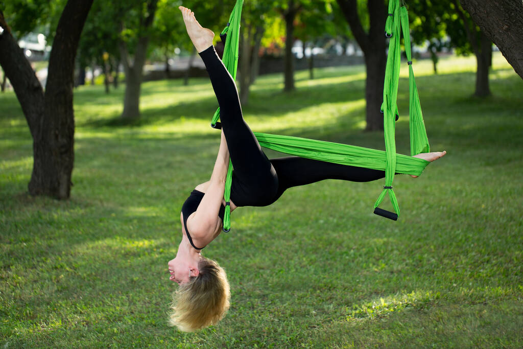 反重力ヨガ、公園でヨガの練習をやっている女性. - 写真・画像