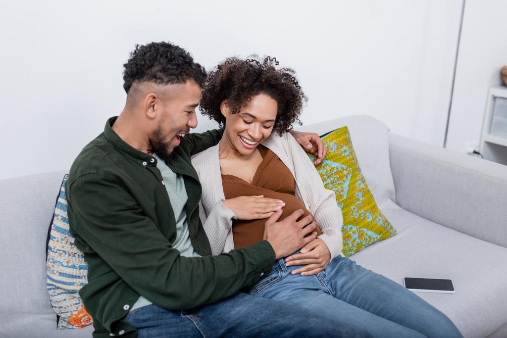 excitado africano americano hombre tocando vientre de embarazada esposa - Foto, Imagen
