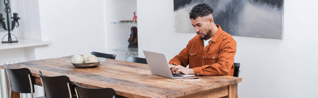 freelancer afro-americano digitando no laptop enquanto trabalhava em casa, banner - Foto, Imagem