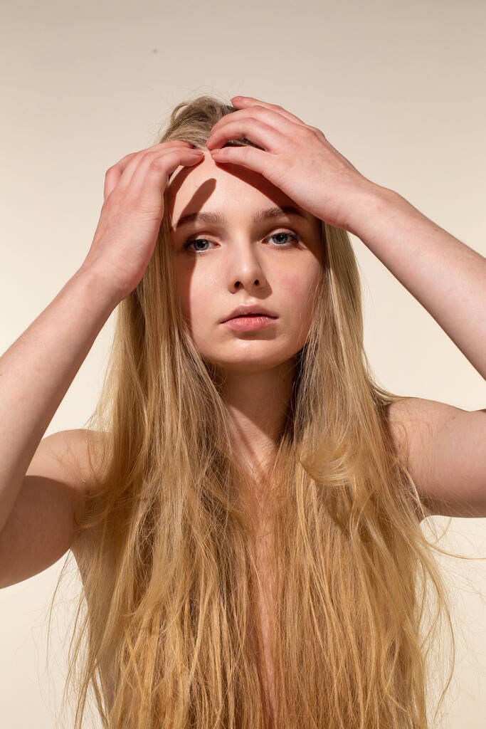Біла молода жінка з світлим волоссям ізольована на бежевому з рукою біля обличчя
 - Фото, зображення