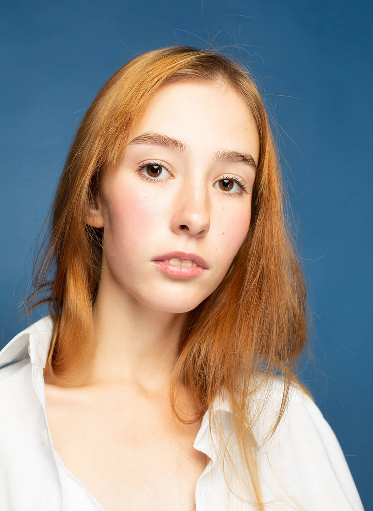 Nahaufnahme Porträt Mädchen mit roten Haaren und weißer Haut isoliert auf blau - Foto, Bild
