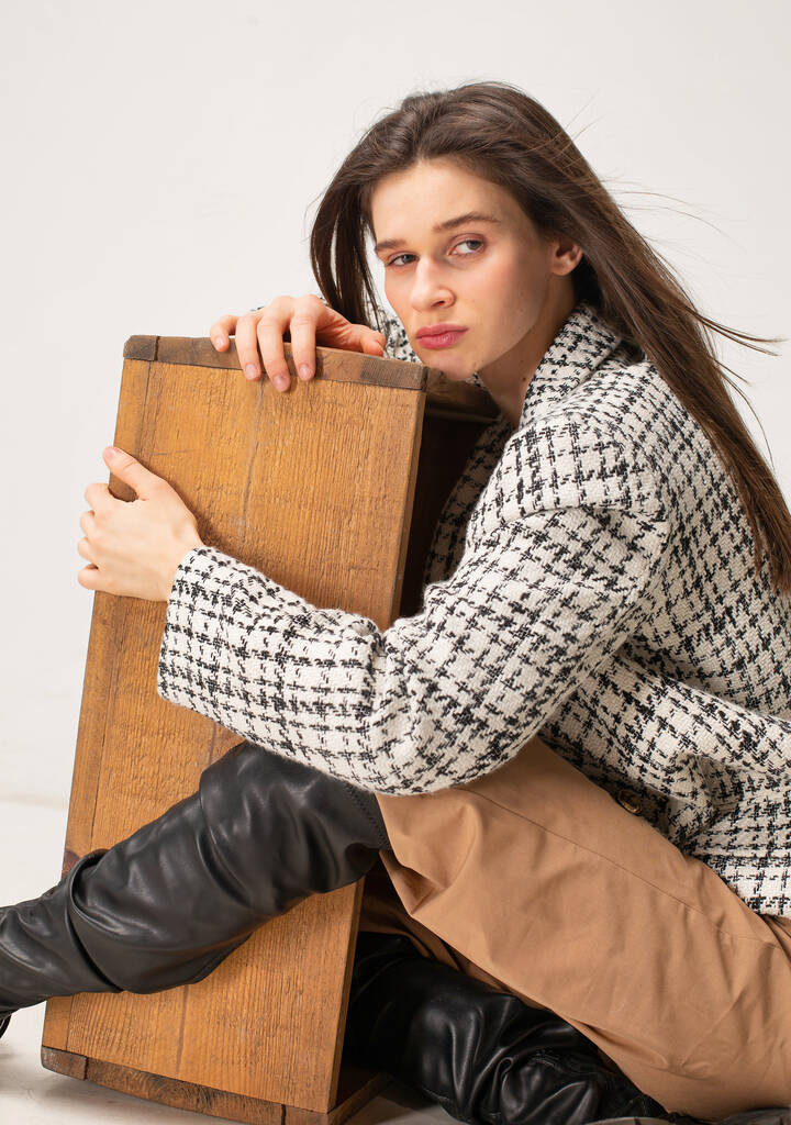 Mujer delgada joven con cabello oscuro aislado en beige abrazando caja de madera - Foto, Imagen