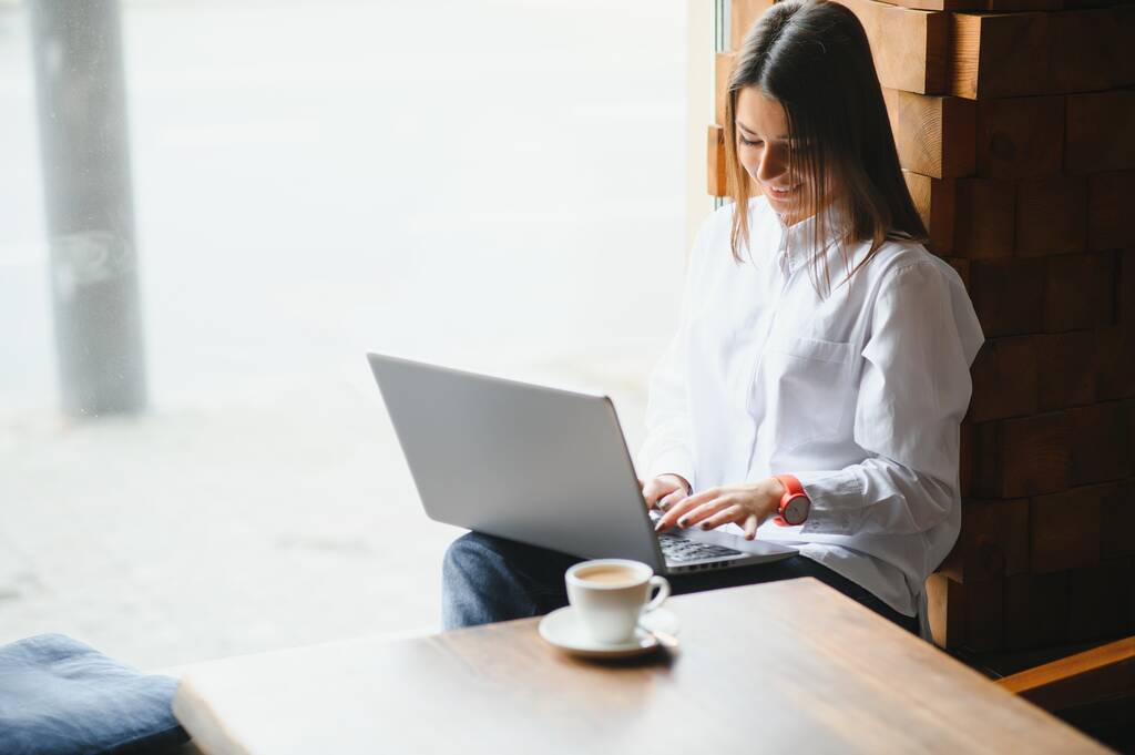 Foto retrato de hermosa mujer atractiva que trabaja en el ordenador portátil escribiendo sentado en la cafetería beber café - Foto, Imagen